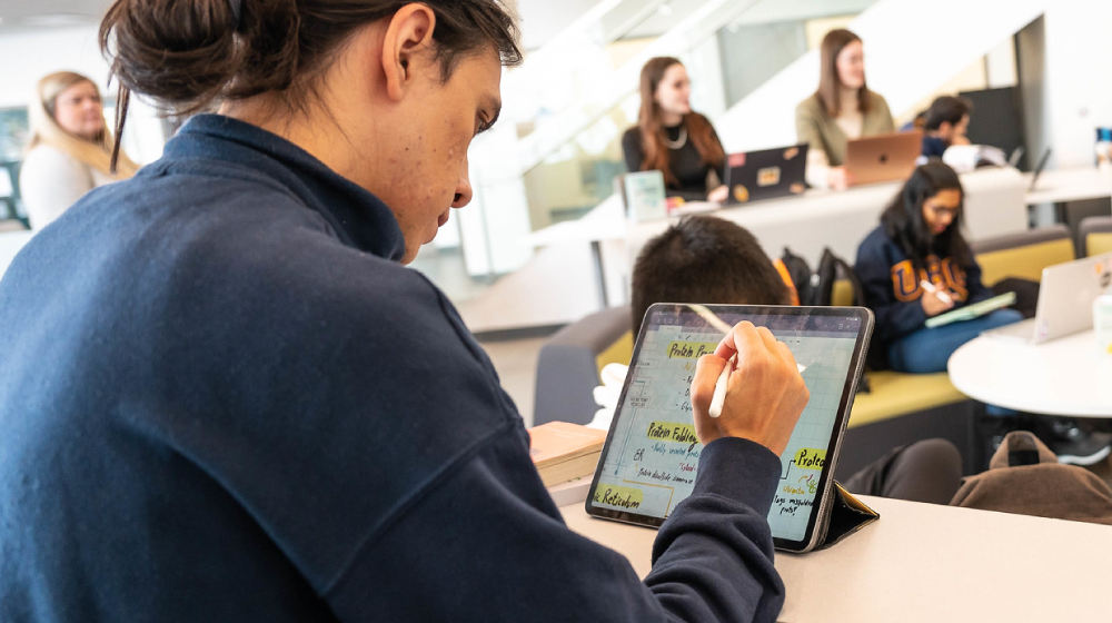 Student using an iPad in a classroom, indoors.